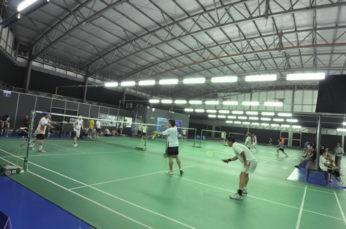 Players training across several badminton courts